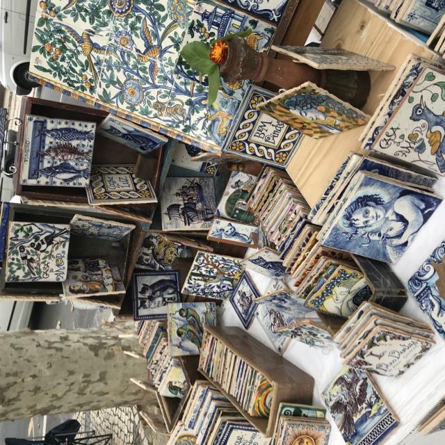 Uliczne stoisko z tradycyjnymi, malowanymi kafelkami ceramicznymi z różnymi wzorami.